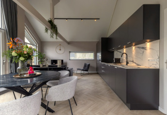 Moderne feriebolig ved Holiday Park «Latour 6», Holland, med sort køkken, spisebord og stilfuld indretning.