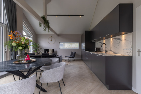 Modern lodge at Holiday Park «Latour 6» in the Netherlands, featuring a sleek black kitchen and dining area.