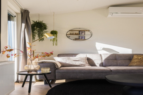 Modernes Wohnzimmer in Holiday Park «Latour 8» mit grauem Sofa, Pflanzen und Wandregal in den Niederlanden.