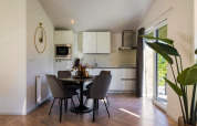 Moderne open keuken en eethoek met ronde tafel, grijze stoelen en schuifpui in Holiday Park Latour 8.