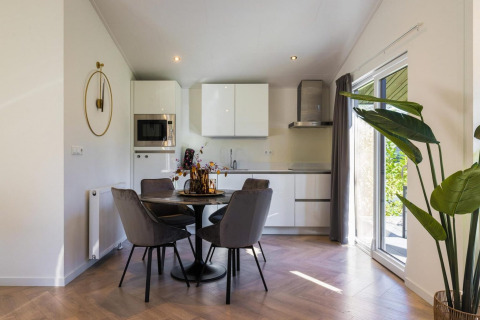 Moderne Küche mit Essbereich, runden Tisch und grauen Stühlen in der Ferienanlage Latour 8, Niederlande.