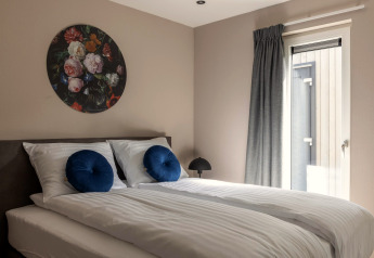 Moderne soveværelse på Holiday Park Latour 6, Nederlandene, med hvide senge og blå puder.
