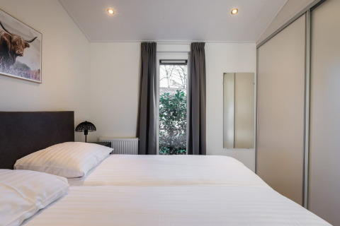 Dormitorio moderno con cama doble, armario y ventana en Holiday Park Latour 8, Países Bajos.