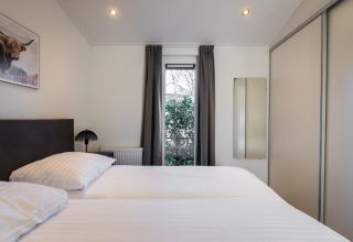 Modernes Schlafzimmer mit Doppelbett, Fenster und Kleiderschrank im Holiday Park Latour 8, Niederlande.