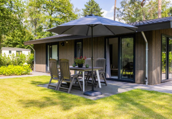Sunny terrace at Holiday Park Latour 8 in the Netherlands, with outdoor dining set, umbrella, and modern lodge.