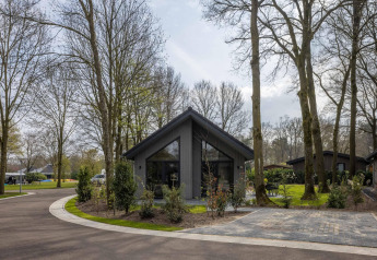 Casa moderna en el parque vacacional Latour 6 en Países Bajos, rodeada de árboles altos y naturaleza tranquila.
