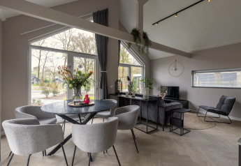 Moderne lodge med store vinduer, stue og spisehjørne med udsigt til naturen i Holiday Park Latour 6.