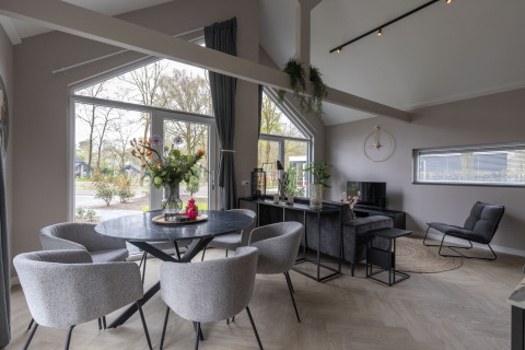 Moderne lodge med store vinduer, stue og spisehjørne med udsigt til naturen i Holiday Park Latour 6.