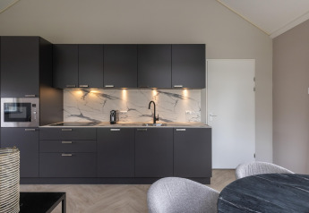 Moderne Küche im Holiday Park «Latour 6» in den Niederlanden mit dunklen Schränken und Marmorwand.