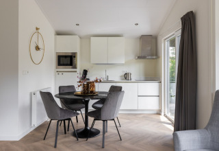 Zona pranzo e cucina moderna con sedie grigie e mobili bianchi presso Holiday Park «Latour 8», Paesi Bassi.