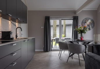 Cocina y comedor modernos con muebles grises y grandes ventanales en Holiday Park Latour 6, Países Bajos.