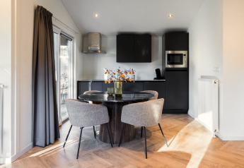 Moderne eet- en keukenruimte in Holiday Park «Latour 8» in Nederland met stijlvolle zwarte inrichting.