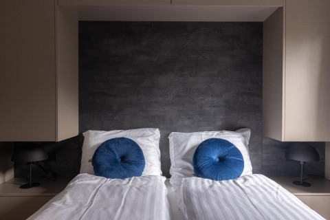 Modern bedroom with two single beds, blue round pillows, and black lamps at Holiday Park Latour 6, Netherlands.