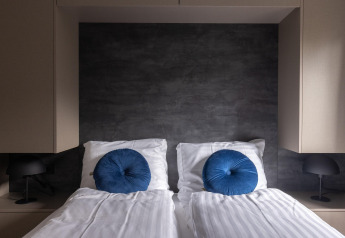 Modernes Schlafzimmer mit zwei Einzelbetten, blauen Kissen und schwarzen Lampen im Holiday Park Latour 6, Niederlande.