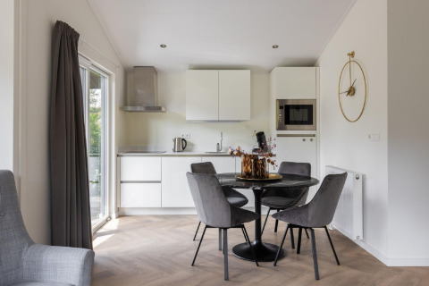 Cucina moderna e zona pranzo con tavolo tondo e sedie grigie all’Holiday Park Latour 8 nei Paesi Bassi.