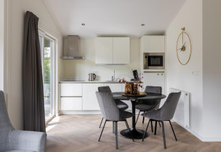 Moderne keuken en eetruimte met ronde tafel en grijze stoelen in Holiday Park Latour 8, Nederland.