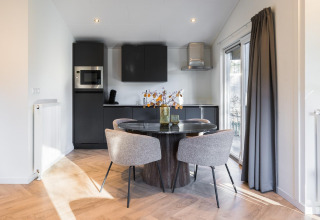 Modern kitchen and dining space at Holiday Park «Latour 8» in the Netherlands, round table and four chairs.