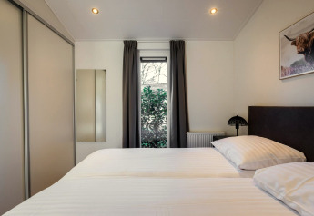 Moderne slaapkamer in Holiday Park Latour 8 in Nederland met tweepersoonsbed, raam en kledingkast.