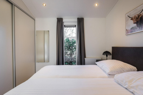 Modern bedroom at Holiday Park Latour 8 in the Netherlands, featuring a double bed, window, and closet.