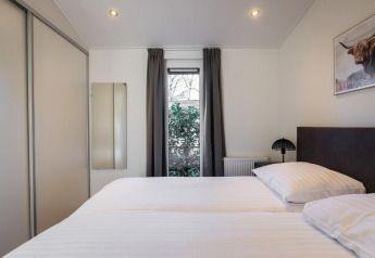 Modern bedroom at Holiday Park Latour 8 in the Netherlands, featuring a double bed, window, and closet.