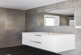 Baño moderno en Holiday Park «Latour 8» en los Países Bajos con gran espejo, lavabo blanco y paredes grises.