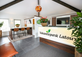 Moderne Rezeption mit Pflanzen und dem Schild 'Vakantiepark Latour' im Ferienpark Latour 6, Niederlande.