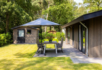 Buitenruimte bij Holiday Park Latour 8 in Nederland met terras, tuinset en parasol in het groen.