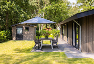 Außenbereich im Holiday Park Latour 8 in den Niederlanden mit Terrasse, Gartenmöbeln und Sonnenschirm.