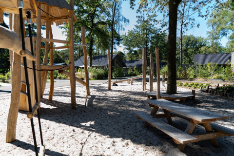 Wooden playground with picnic tables and sand at Holiday Park Latour 8 in the Netherlands, sunny day.