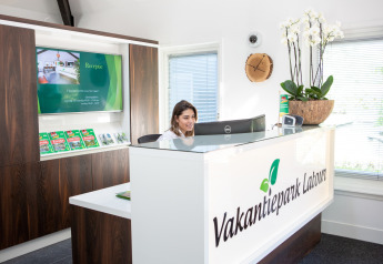 Rezeptionistin am Empfangstresen im Vakantiepark Latour, mit Prospekten, Dekoration und moderner Atmosphäre.