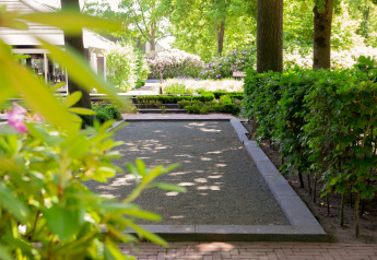 Rustige tuin bij Holiday Park «Latour 8» in Nederland met hagen, bomen en bloeiende bloemen.