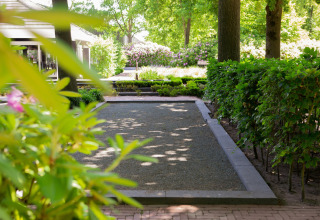 Ruhiger Garten im Holiday Park «Latour 8» in den Niederlanden mit Hecken, Bäumen und Blumen.