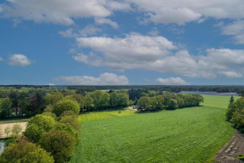 Green fields and trees beneath a blue sky with clouds at Holiday Park Latour 6 in the Netherlands.