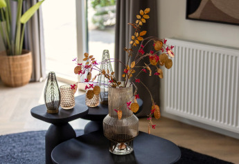 Stijlvolle glazen vaas met droogbloemen op zwarte tafels in Holiday Park Latour 8, Nederland.