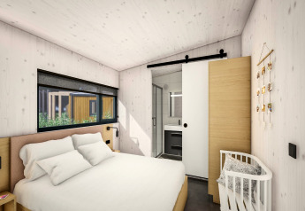Moderne slaapkamer met tweepersoonsbed, ledikant en schuifdeur naar badkamer in Holiday Park Klein Vink 25.