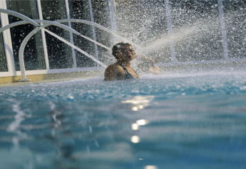 Personne profitant de jets d’eau dans une piscine intérieure d’un hébergement glamping moderne.