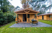 Vue extérieure d’un lodge bien-être pour 4 personnes aux Pays-Bas, entouré de verdure et d’arbres.