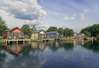 Holiday cabins on stilts over the lake at Klein Vink 24, Netherlands, surrounded by trees and calm water.