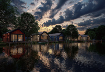Vue nocturne du Holiday Park Klein Vink 24 aux Pays-Bas avec des lodges au bord d’un lac paisible.