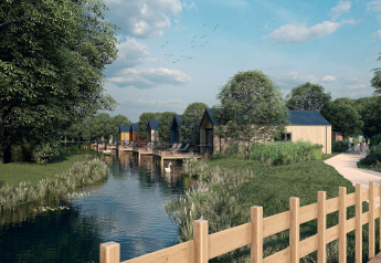 Holiday Park Klein Vink 24 in the Netherlands, modern lodges by the river, lush trees, and walking path.
