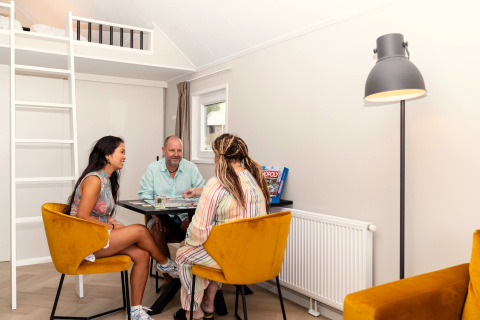 Drie mensen spelen een bordspel in de lichte, moderne woonkamer van Berg Lodge in Nederland.