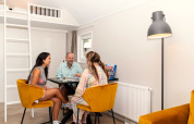 Three people enjoying a board game in a bright, cozy living room at Berg Lodge in the Netherlands.