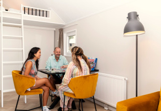 Drie mensen spelen een bordspel in de lichte, moderne woonkamer van Berg Lodge in Nederland.