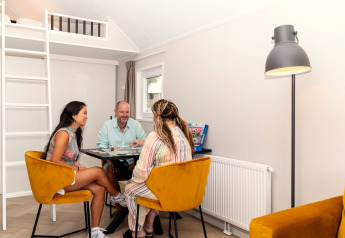 Three people enjoying a board game in a bright, cozy living room at Berg Lodge in the Netherlands.