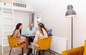 Three people enjoying a board game in a bright, cozy living room at Berg Lodge in the Netherlands.