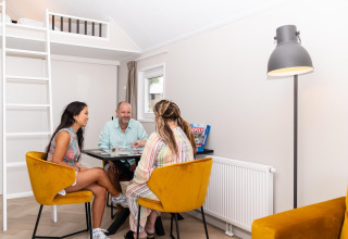 Tre personer hygger sig med et brætspil i en moderne, lys stue på Berg Lodge i Holland.