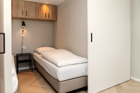 Moderne slaapkamer in Berg Lodge in Nederland met eenpersoonsbed, nachtkastje en wandlamp.