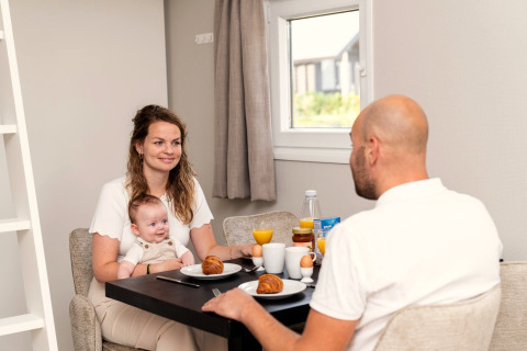 Gezin geniet samen van ontbijt bij Berg Lodge in Nederland, met croissants en sinaasappelsap.