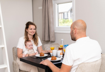 Family enjoying breakfast together at Berg Lodge in the Netherlands, with croissants and orange juice.