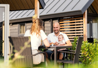 Famille prenant le petit-déjeuner dehors à la Berg Lodge aux Pays-Bas, assise à une table avec leur bébé.
